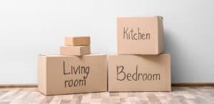 Cardboard boxes labeled with the room they should go to.