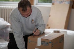 Moving man writes a label on a box.